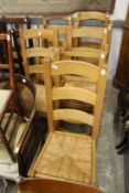 A set of eight modern oak and rush seated ladder back dining chairs.