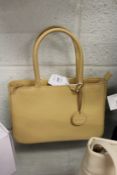 A beige leather handbag with dust cover.