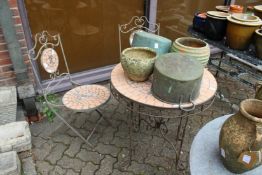 A modern wrought iron circular patio table and a pair of matching folding chairs.