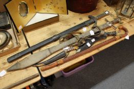 An eastern dagger, a Gurkha kukri, a Chinese sword, another sword and a walking stick.