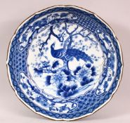 A JAPANESE MEIJI BLUE & WHITE PORCELAIN DISH - decorated with a peacock amongst flora, base