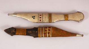 TWO ISLAMIC WHITE METAL AND INLAID DAGGERS -- each inlaid with semi precious gems, 28.5cm (2)