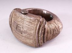 A PERSIAN WHITE METAL SLAVE BANGLE, with engraved and embossed decoration, 12cm wide.