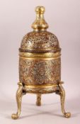 AN ISLAMIC SILVER AND COPPER INLAID BRASS INCENSE BURNER AND COVER, on tripod legs, with roundels