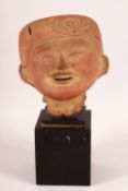 A 17TH/18TH CENTURY EYGPTIAN STONE BUST of a smiling figure in a head dress, elevated on a wooden