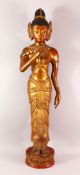 A LARGE THAI GILT AND RED LACQUER CARVED WOOD FIGURE, standing on a lotus base, 104cm high.
