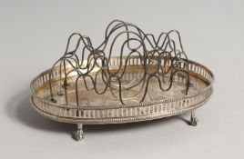 A GEORGE III SILVER OVAL TOAST RACK with wire division on claw and ball feet. London 1774, maker