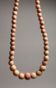 A STAINED IVORY GRADUATED BEAD NECKLACE of forty five beads 13ins long