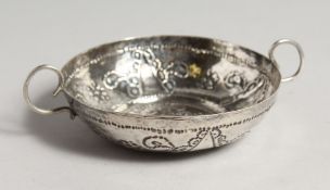 A CIRCULALR WINE TASTER repousse with fruiting vines and plain handles 4ins diameter, makers mark