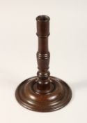 AN 18TH CENTURY TURNED WOOD CANDLESTICK with large circular base 10.5ins high