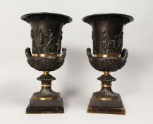 A PAIR OF DECORATIVE CLASSICAL STULE BRONZE TWIN HANDLED URNS, mounted on square flourite bases 14.