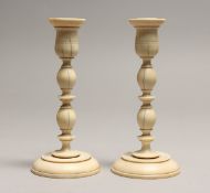 A PAIR OF TURNED IVORY CANDLESTICKS 5.75ins high.
