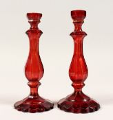 A PAIR OF RUBY GLASS CANDLESTICKS 8.5ins high