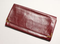 A CARTIER RED LEATHER FOLDING CLUTCH BAG used, 11ins wide.