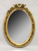 A LARGE DECORATIVE OVAL GILT FRAMED WALL MIRROR. 4ft 2ins high x 3ft wide.
