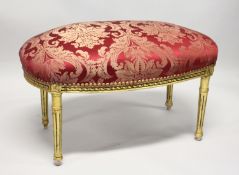 A GILT FRAMED STOOL UPHOLSTERED IN RED DAMASK. 2ft 11ins long x 1ft 8ins wide x 1ft 8ins high.