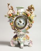 A CONTINENTAL PORCELAIN CUPID AND FLOWER ENCRUSTED CLOCK, with blue and white Roman numerals.