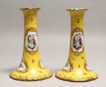 A PAIR OF DRESDEN PORCELAIN CANDLESTICKS, yellow ground painted and gilded with vignettes of a
