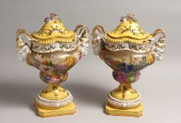 A PAIR OF CONTINENTAL PORCELAIN TWO HANDLED (RAM'S MASK) URNS, COVERS AND STANDS, painted with