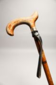 A RUSTIC WALKING CANE with leather straps 2ft 8ins long