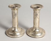 A PAIR OF SILVER CANDLESTICKS, each with ribbon and swag embossed decoration, Birmingham 1904, 4.
