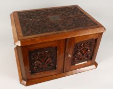 A GOOD VICTORIAN CARVED OVAL TABLE TOP CABINET, the top and doors with carved decoration, the