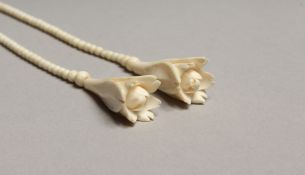 A DELICATE CARVED IVORY NECKLACE carved with two flowers 30ins long.
