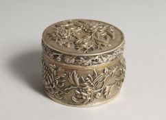 A CHINESE SILVER CIRCULAR BOX AND COVER, repousse decorated with flowers 3ins diameter