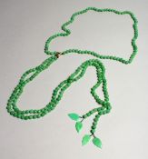 A LONG STRING OF JADE BEADS with gold clasp.