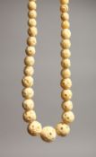 A CARVED IVORY GRADUATED BEAD NECKLACE on fifty three beads 16ins long
