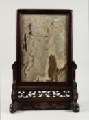 A CHINESE TABLE SCREEN, the pierced and carved wood frame inset with a hardstone plaque. 23ins