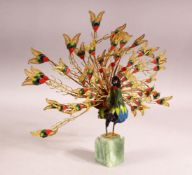 A DECORATIVE GILT METAL AND ENAMELLED MODEL OF A PEACOCK, plumage on full display, mounted on an
