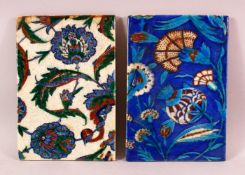TWO IZNIK STYLE POTTERY TILES, with blue and white grounds with floral decoration, 23.5cm x 26cm.