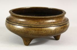 A CHINESE BRONZE CIRCULAR CENSER, supported on three feet, 16cm diameter.