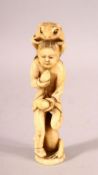 A JAPANESE CARVED IVORY OKIMONO of a boy eating peaches with a toad on his back and a toad at his
