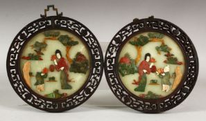 A PAIR OF CHINESE CIRCULAR HARDSTONE PANELS, each depciting figures in a garden, within pierced