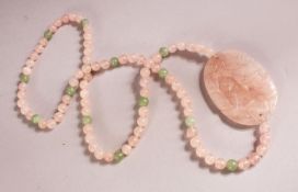 A CHINESE ROSE QUARTZ CARVED NECKLACE / PENDANT - with a carved pendant with beads, 74cm approx.