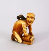 A JAPANESE MEIJI PERIOD CARVED IVORY SMALL OKIMONO OF A RAT CATCHER, the man leaning over his trap