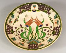 AN IZNIK STYLE POTTERY DISH, possibly European, decorated with stylised flowers, 25cm diameter.