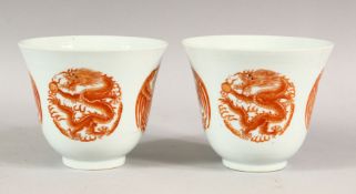 A PAIR OF RED AND WHITE CUPS, each with four panels of dragons and phoenix, 9.5cm high.