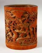 A CHINESE CARVED BAMBOO BRUSH POT, the body carved with landscape scene with figures, 18cm high.