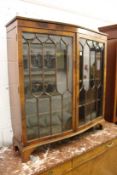 A mahogany serpentine fronted two door display cabinet.