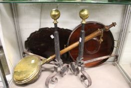A pair of early wrought iron and brass fire dogs, a brass bed warming pan and two wooden trays.
