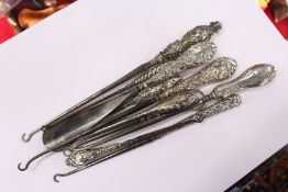 A quantity of silver handled button hooks and similar items.