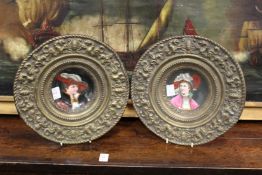 A pair of continental porcelain portrait dishes with impressed brass mounts.
