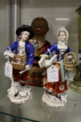A pair of porcelain figures, one of a boy selling rabbits, the other a girl with a goose under one