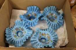 A set of four opaque blue glass frilly edged dishes with floral decoration.