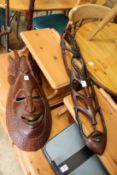 Two carved African masks and a Chinese carved wood lamp stand.