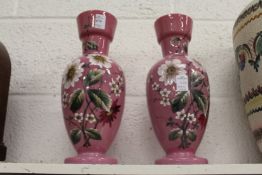 A pair of floral decorated pink opaque glass vases.