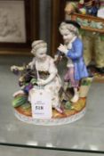A 19th century porcelain group of a boy playing a pipe, a young girl seated feeding grapes to a